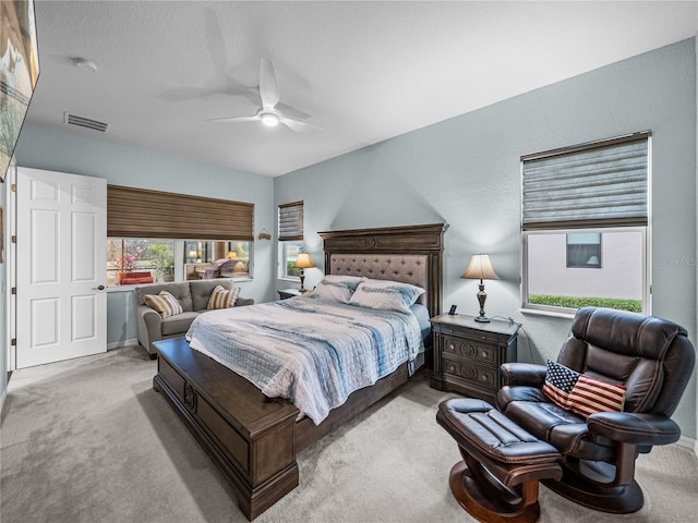 bedroom featuring carpet floors, a textured wall, visible vents, and ceiling fan