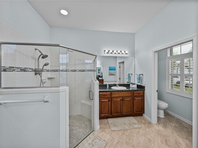 bathroom with vanity, a shower stall, toilet, and baseboards