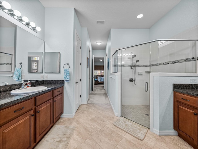 ensuite bathroom featuring a stall shower, visible vents, and a sink