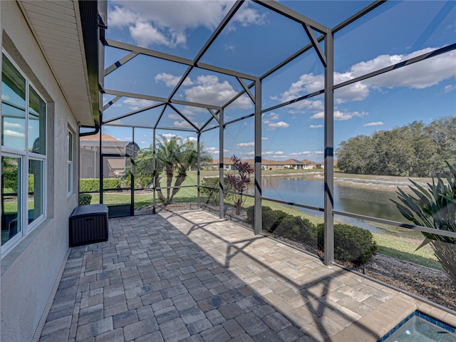 view of patio / terrace featuring glass enclosure and a water view