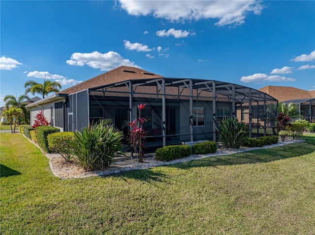 rear view of property with glass enclosure and a yard