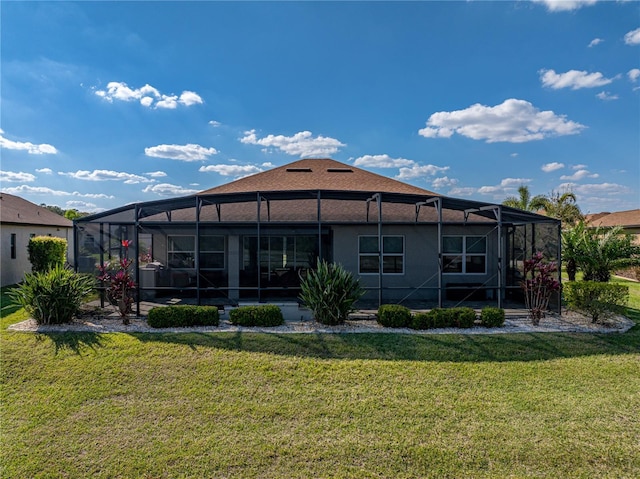 back of property with glass enclosure, a yard, and stucco siding