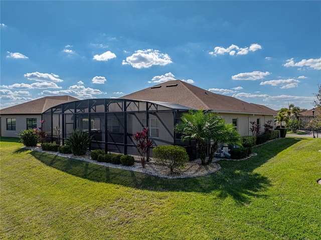 rear view of property featuring a lanai, a yard, and stucco siding