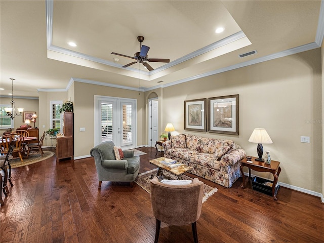 living room with wood-type flooring, a raised ceiling, visible vents, and baseboards