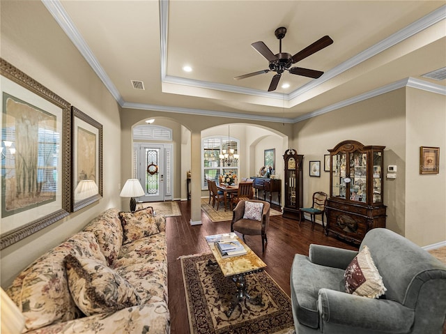 living room with arched walkways, dark wood-style flooring, visible vents, a tray ceiling, and crown molding