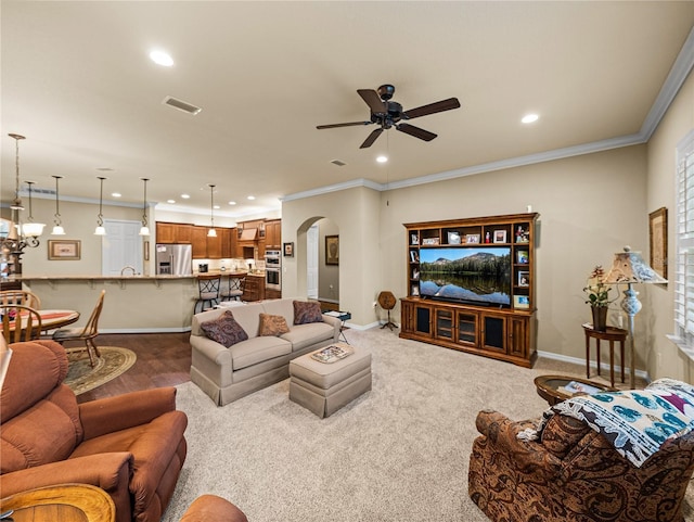 living room with ornamental molding, arched walkways, baseboards, and ceiling fan with notable chandelier