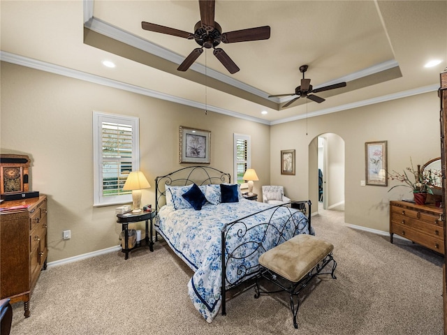 bedroom featuring light carpet, baseboards, arched walkways, and a raised ceiling