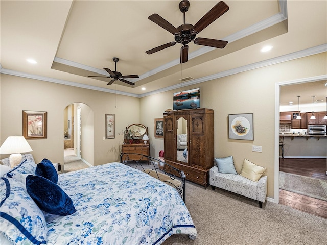 bedroom with visible vents, arched walkways, ornamental molding, a tray ceiling, and carpet floors