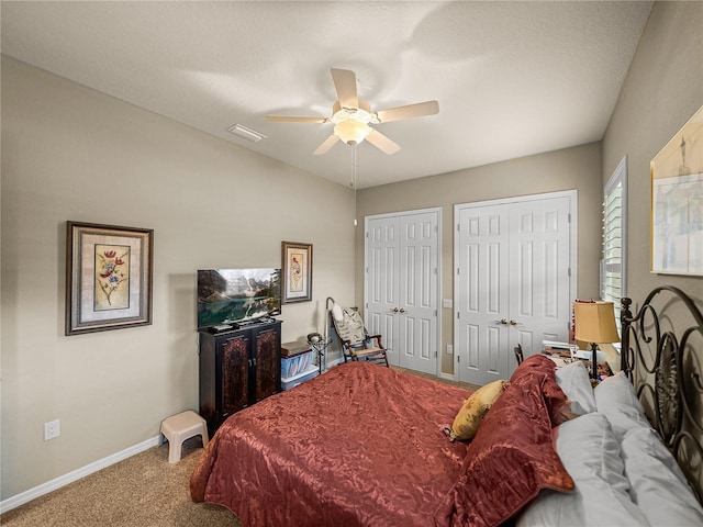 carpeted bedroom with ceiling fan, two closets, visible vents, and baseboards