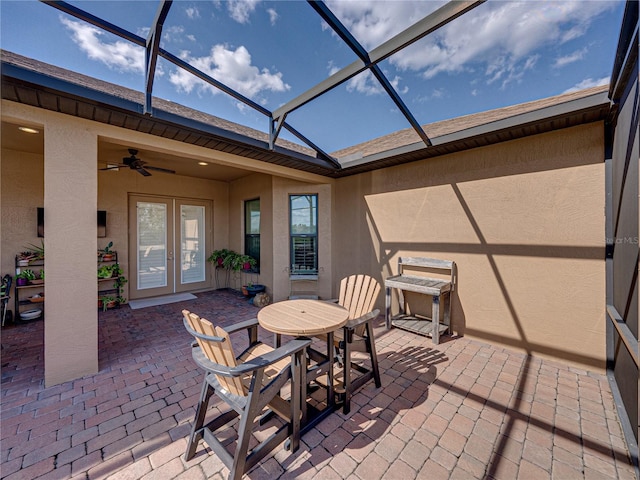 view of patio / terrace featuring ceiling fan, glass enclosure, french doors, and outdoor dining space