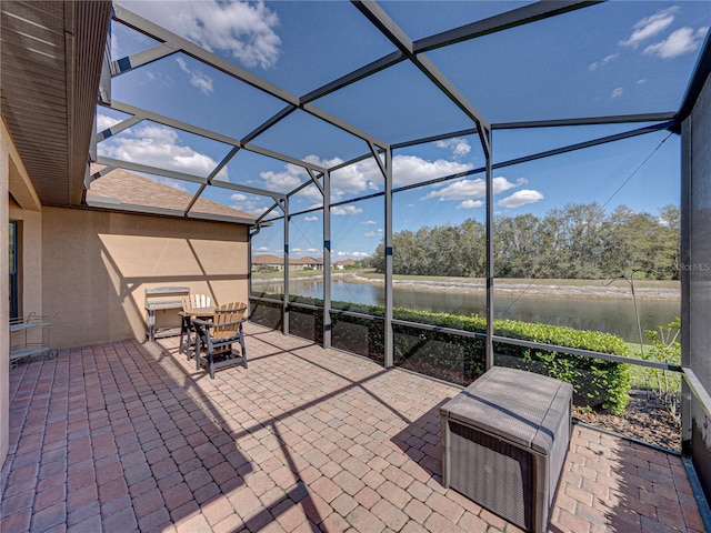 view of patio / terrace featuring a lanai, a water view, and outdoor dining area