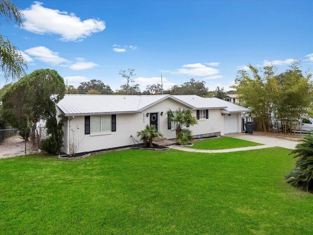 back of property featuring driveway, a lawn, metal roof, an attached garage, and brick siding