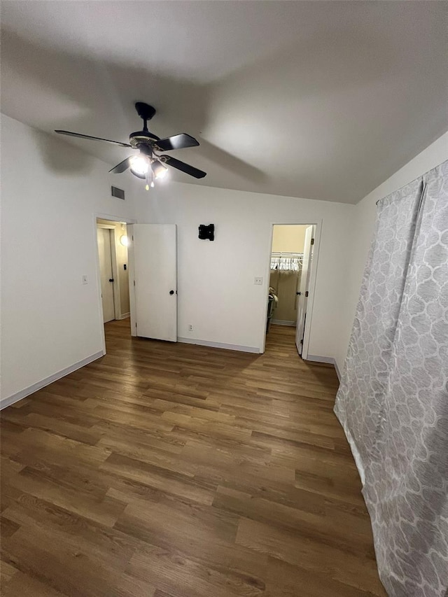 empty room featuring a ceiling fan, dark wood-style flooring, visible vents, and baseboards