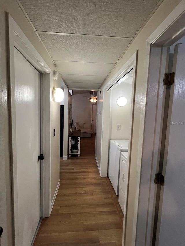 hall with independent washer and dryer, a textured ceiling, and wood finished floors