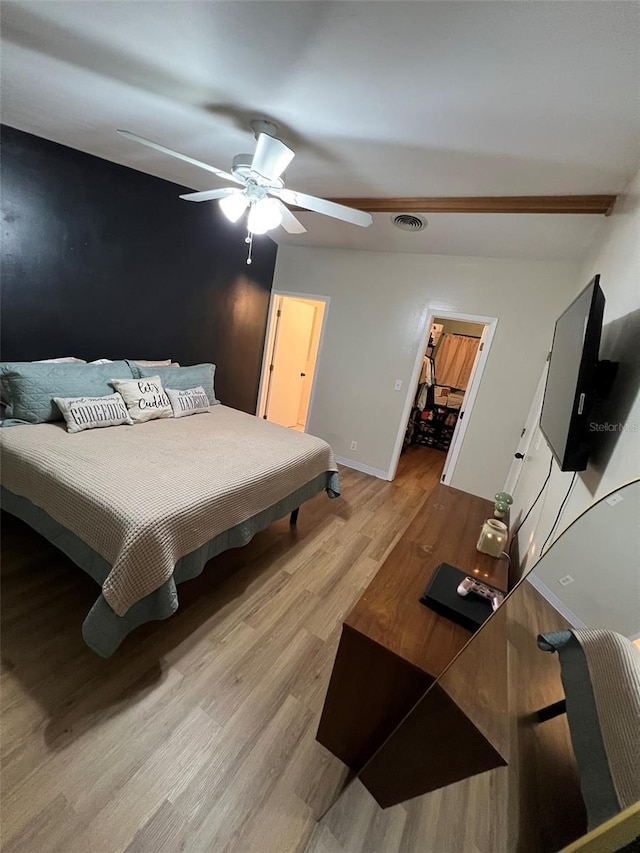 bedroom with visible vents, light wood-style flooring, a spacious closet, ceiling fan, and baseboards