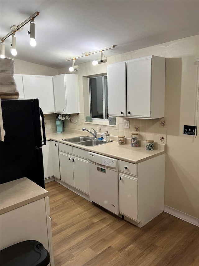 kitchen with light countertops, freestanding refrigerator, white cabinets, white dishwasher, and a sink