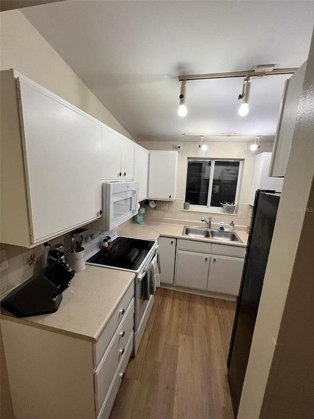 kitchen with white appliances, white cabinets, a sink, and light countertops