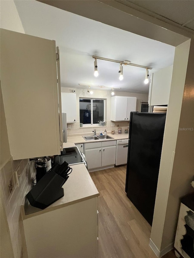 kitchen featuring tasteful backsplash, light countertops, white cabinets, a sink, and white appliances