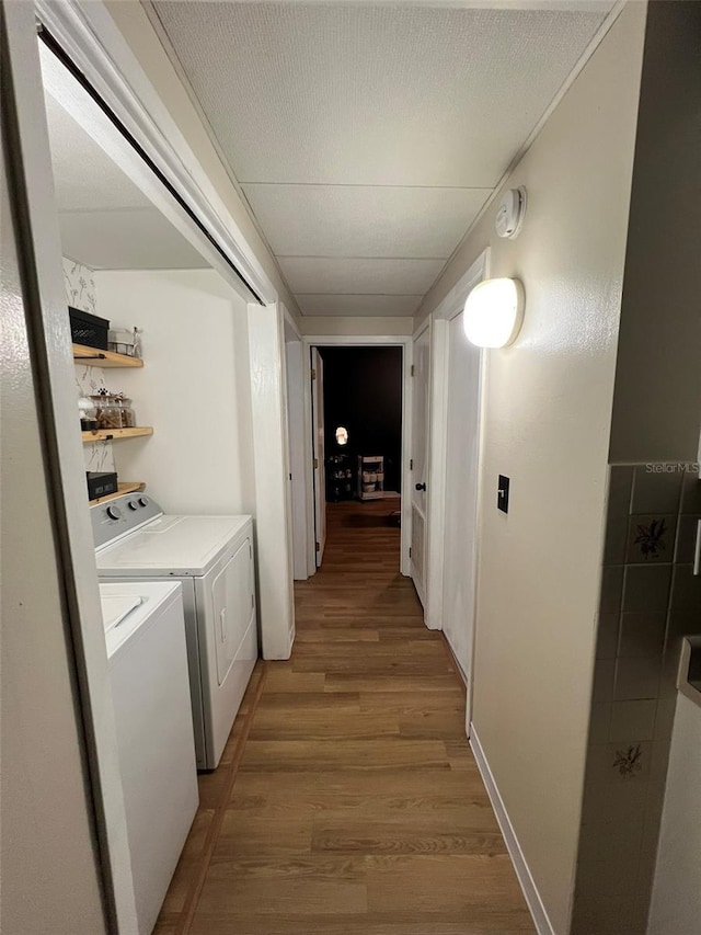 hallway with washer and clothes dryer, a textured ceiling, and wood finished floors