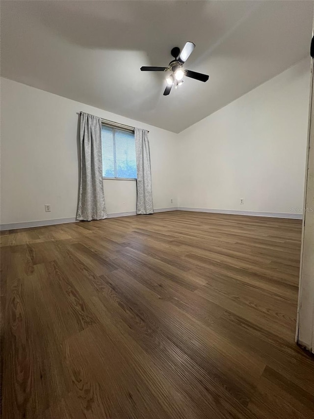 unfurnished room with lofted ceiling, a ceiling fan, baseboards, and dark wood-style flooring