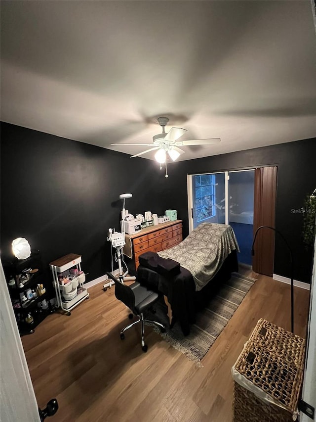 bedroom with ceiling fan, wood finished floors, and baseboards