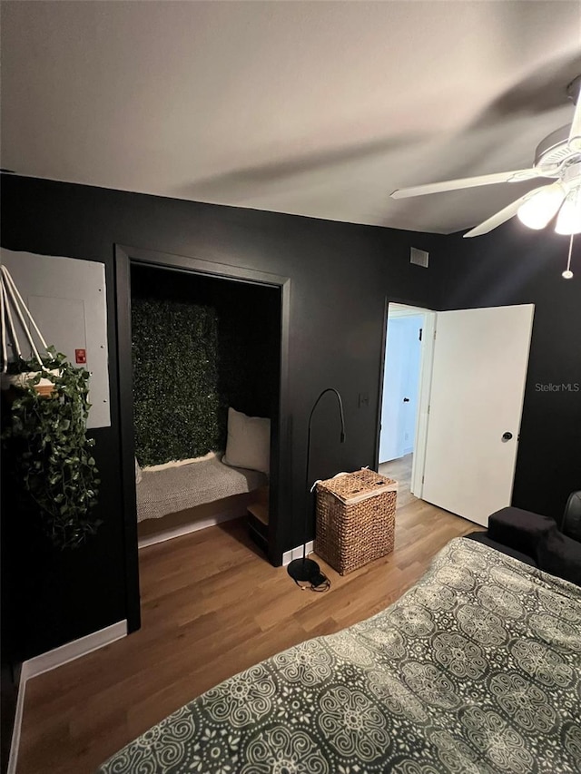 bedroom with a ceiling fan, visible vents, and wood finished floors