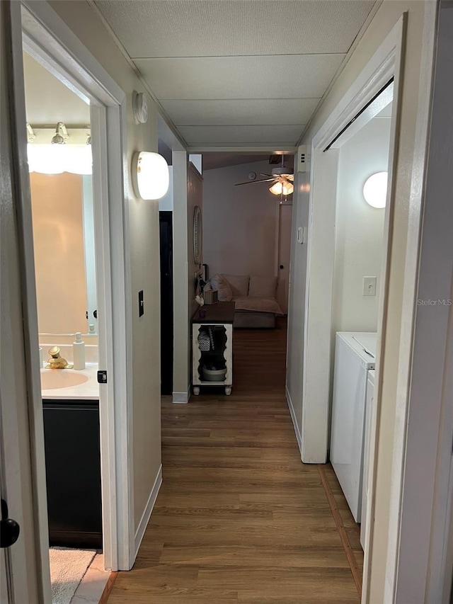 hallway with wood finished floors, a sink, and independent washer and dryer