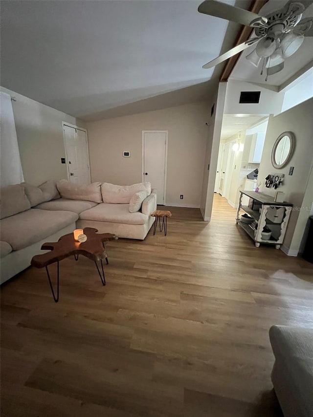 living area featuring baseboards, visible vents, vaulted ceiling, and wood finished floors