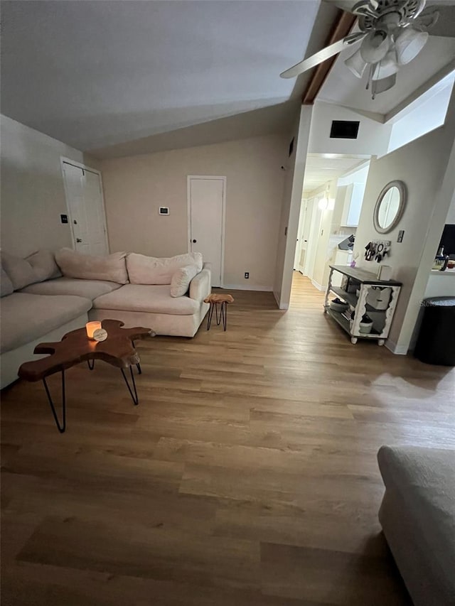 living area featuring light wood finished floors, visible vents, baseboards, ceiling fan, and vaulted ceiling