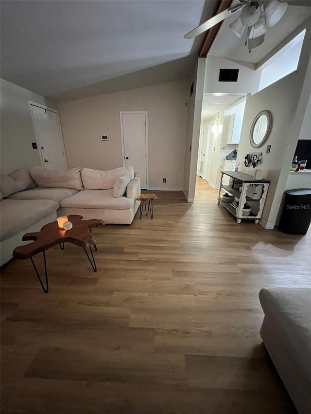 living room featuring vaulted ceiling, ceiling fan, baseboards, and light wood-style floors