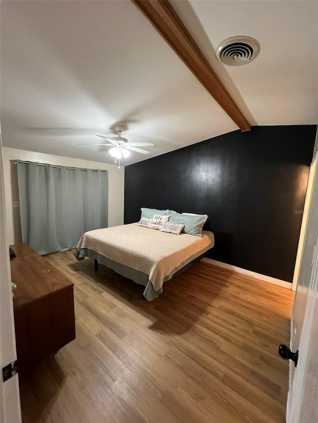 bedroom with baseboards, visible vents, lofted ceiling with beams, ceiling fan, and wood finished floors