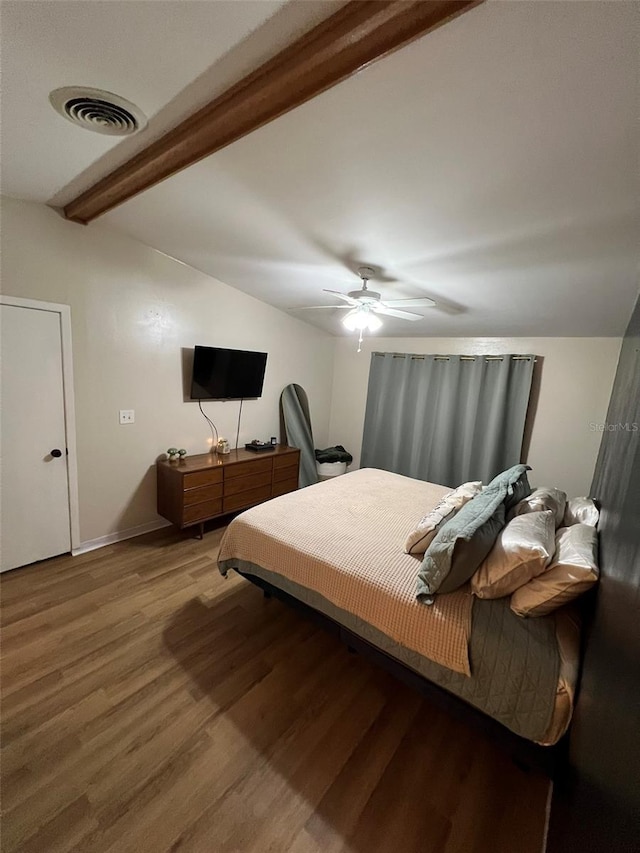 bedroom with visible vents, lofted ceiling with beams, ceiling fan, wood finished floors, and baseboards