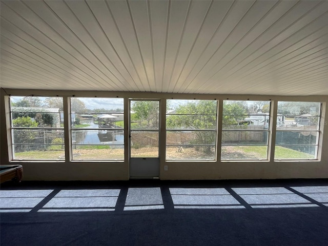 unfurnished sunroom featuring plenty of natural light, a water view, and wood ceiling