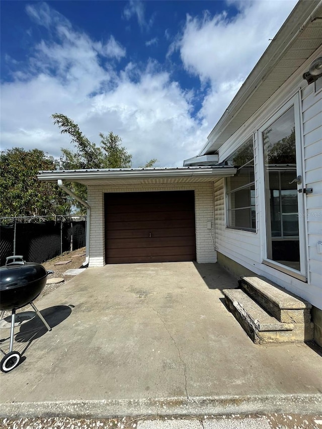 garage with concrete driveway and fence