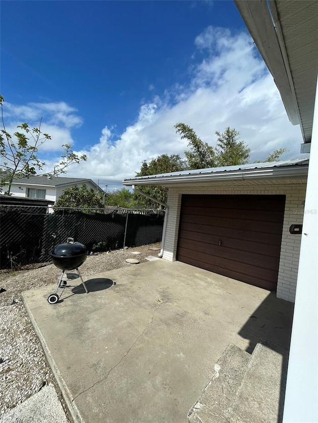 view of patio with a garage, area for grilling, fence, and an outdoor structure