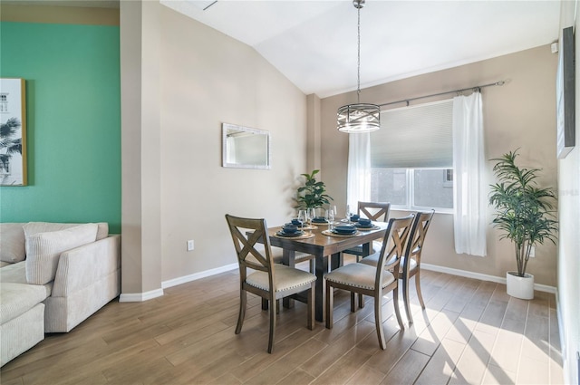 dining room featuring vaulted ceiling, baseboards, and light wood-style floors