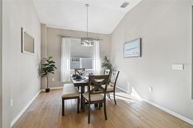 dining area featuring baseboards, lofted ceiling, visible vents, and light wood-style floors