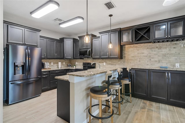 kitchen with visible vents, appliances with stainless steel finishes, decorative light fixtures, a peninsula, and light stone countertops