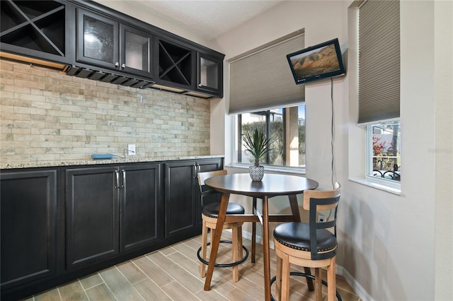 bar with wood tiled floor, a textured ceiling, baseboards, and backsplash