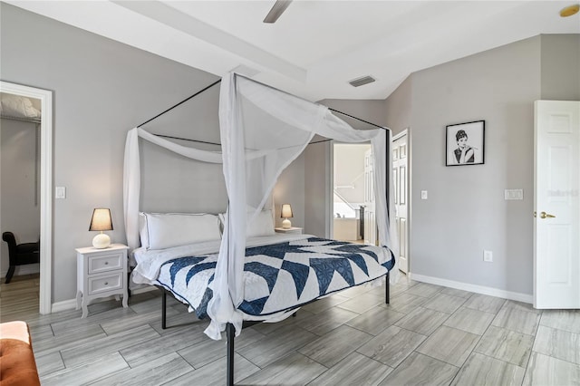 bedroom with wood finish floors, a ceiling fan, visible vents, baseboards, and ensuite bath