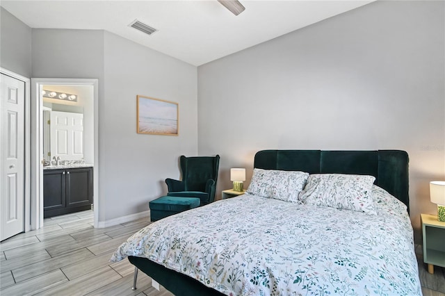 bedroom with ensuite bathroom, ceiling fan, wood finish floors, visible vents, and baseboards