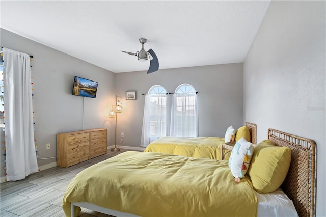 bedroom with light wood finished floors, a ceiling fan, and baseboards