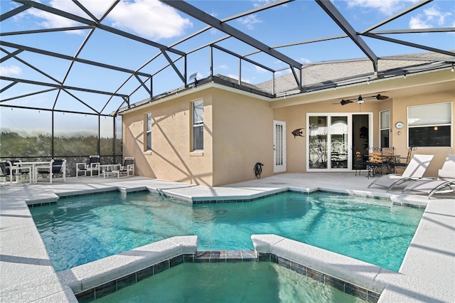 view of swimming pool with ceiling fan, glass enclosure, a patio, and a pool with connected hot tub