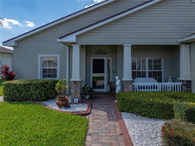 view of exterior entry with covered porch and stucco siding