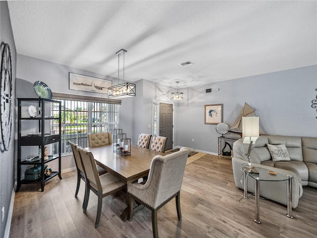 dining area featuring baseboards, visible vents, and wood finished floors