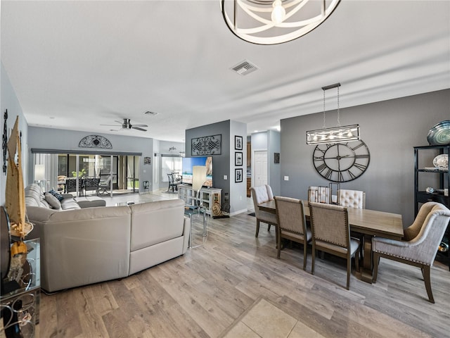 dining area with visible vents, light wood-style flooring, baseboards, and ceiling fan with notable chandelier