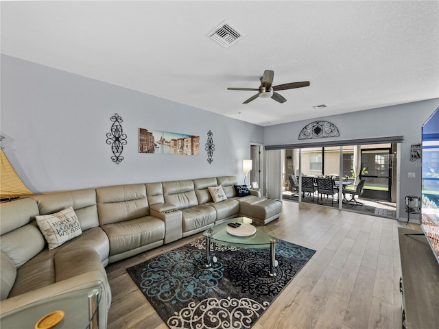 living area with ceiling fan, a textured ceiling, wood finished floors, and visible vents