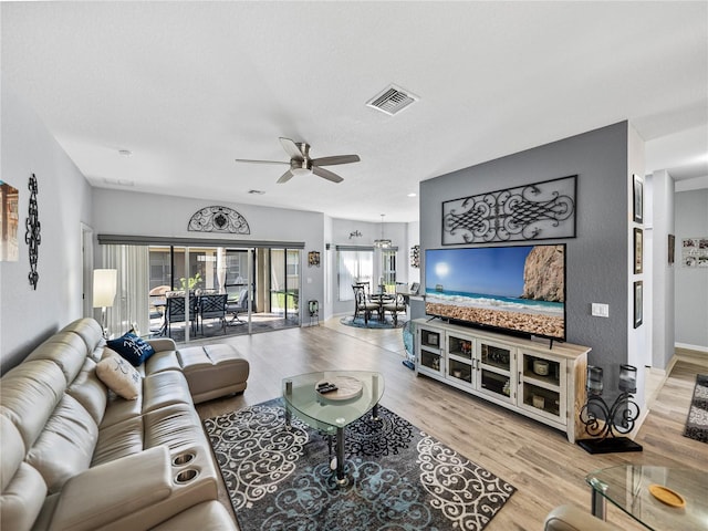 living room with a ceiling fan, visible vents, and wood finished floors