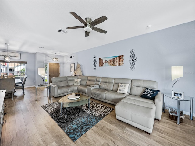 living room with a ceiling fan, baseboards, visible vents, and wood finished floors