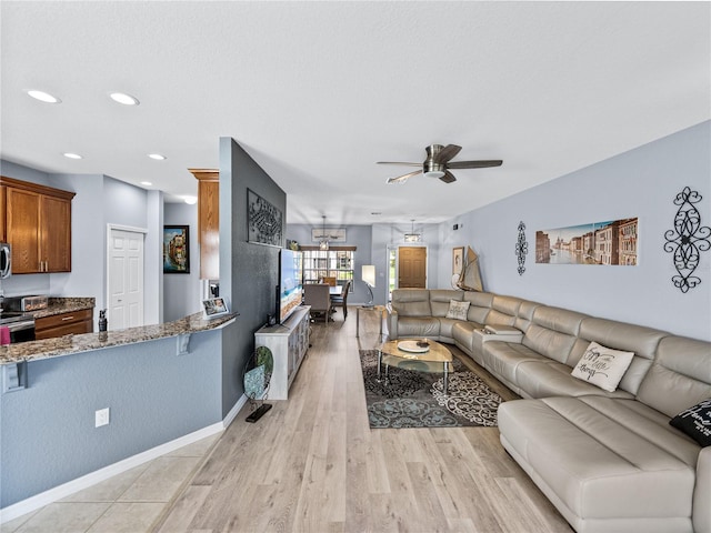 living room with light wood-style floors, baseboards, a ceiling fan, and recessed lighting